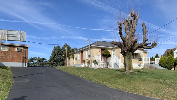 Une rue résidentielle bordée de maisons, avec un arbre et un ciel dégagé.