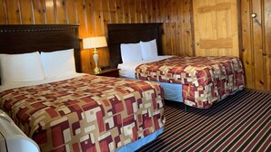 Une chambre d’hôtel avec deux lits, des lambris en bois, une moquette à rayures et une porte en bois.