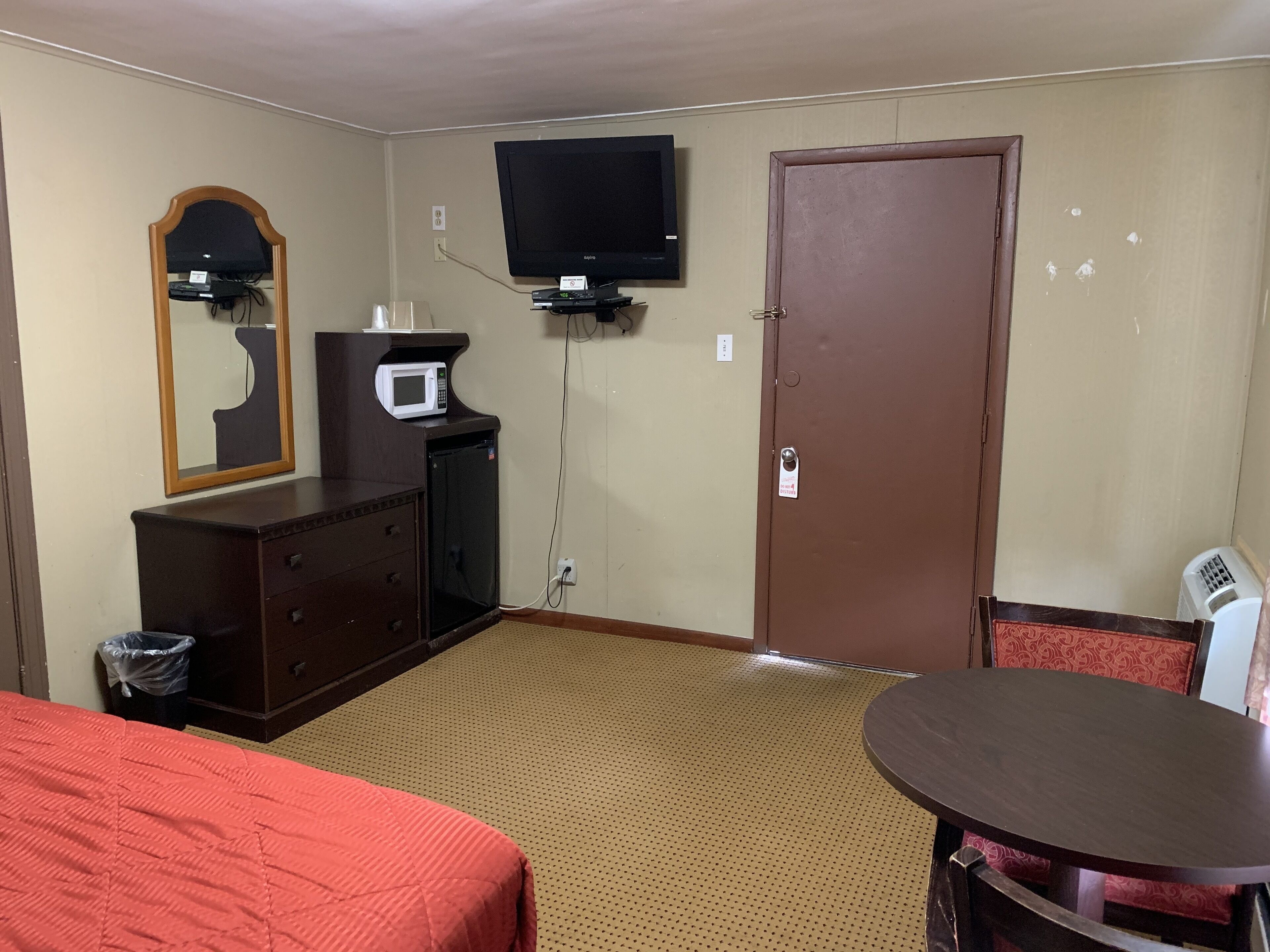 Ein Hotelzimmer mit einem Bett, einem Schrank, einer Mikrowelle, einem Fernseher und einer Tür.