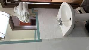 Une salle de bain avec un lavabo blanc, un miroir et un porte-serviettes.