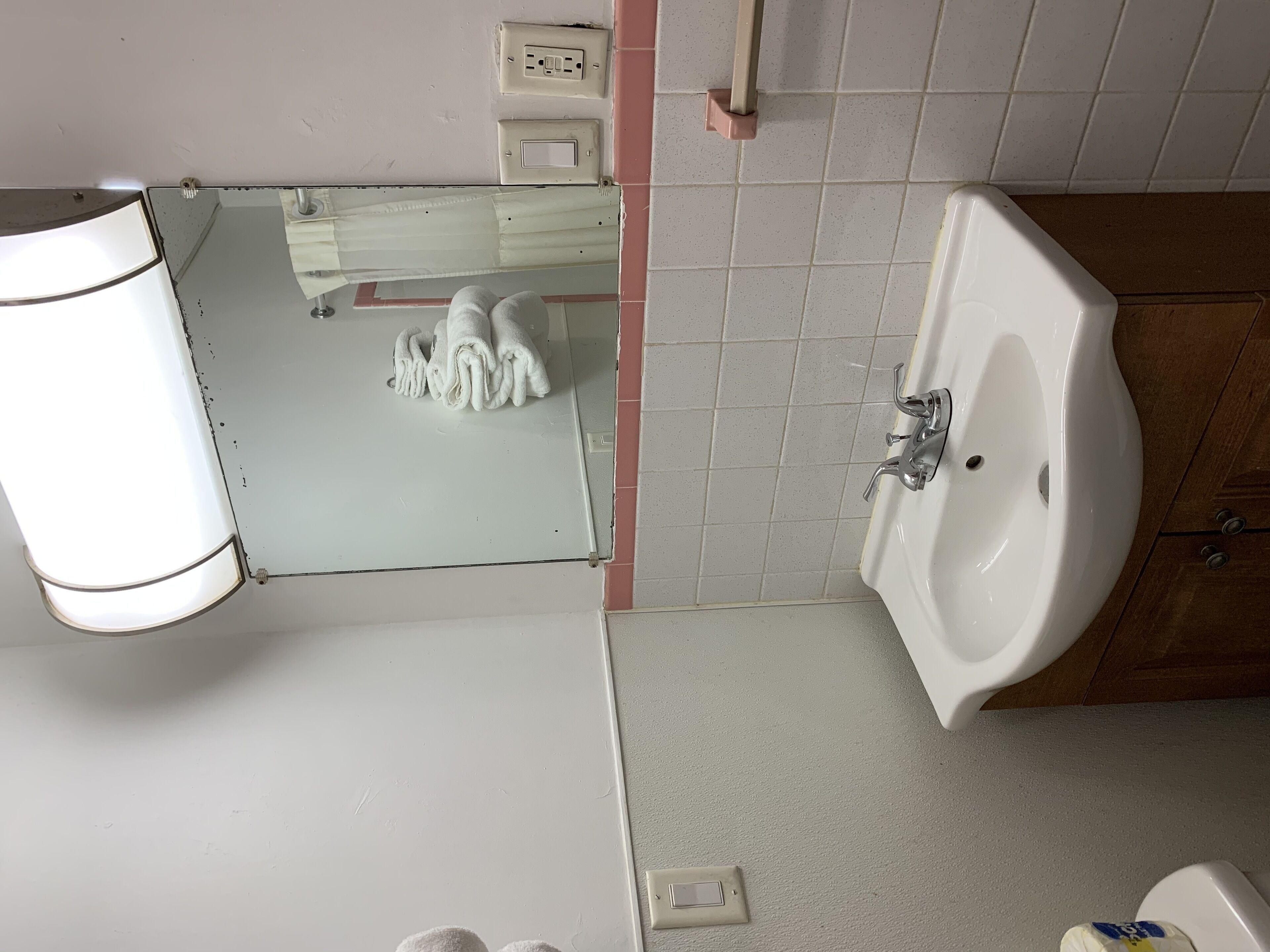 Ein Badezimmer mit Waschbecken, Spiegel und Handtuchhalter.