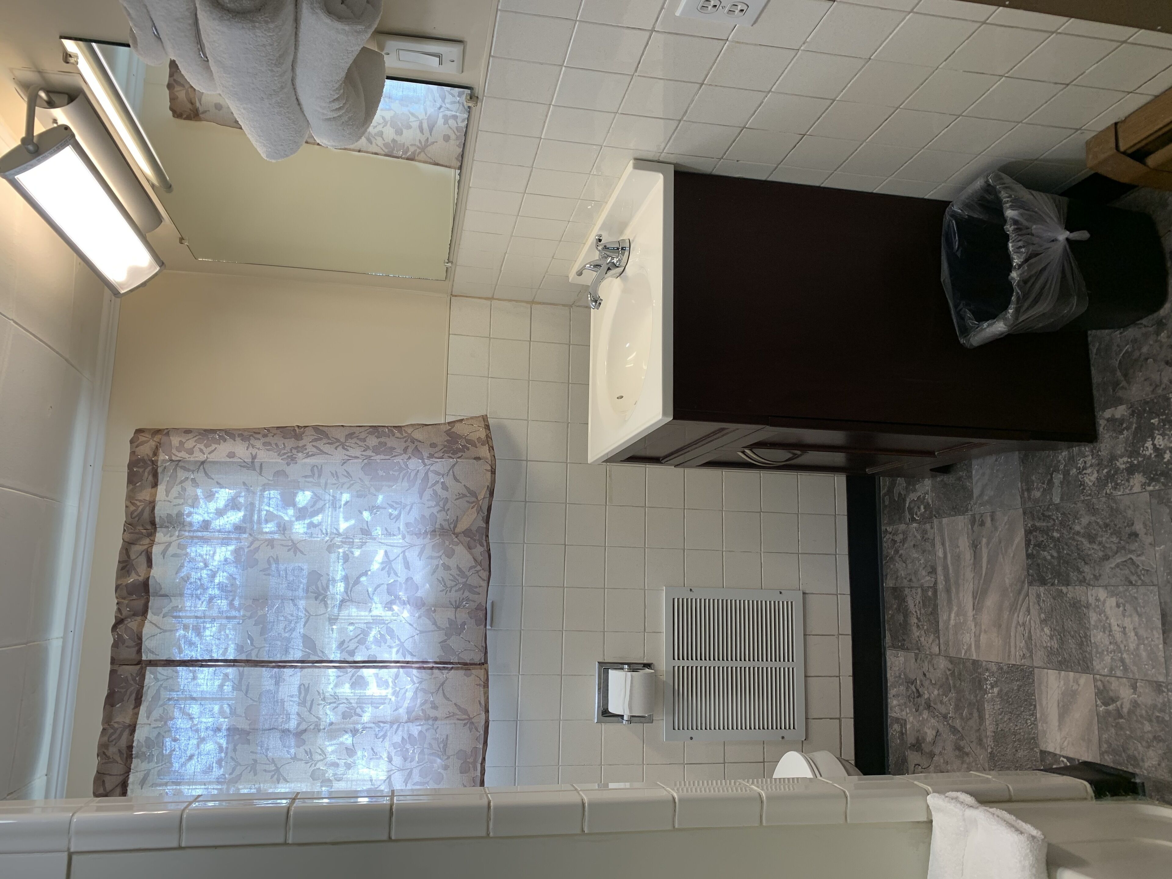 A bathroom with a bathtub, a toilet, a sink, a shower curtain, and a towel rack.