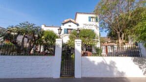 Hotel Boutique Villa Elisa, con fachada blanca, contraventanas azules y techo de tejas.