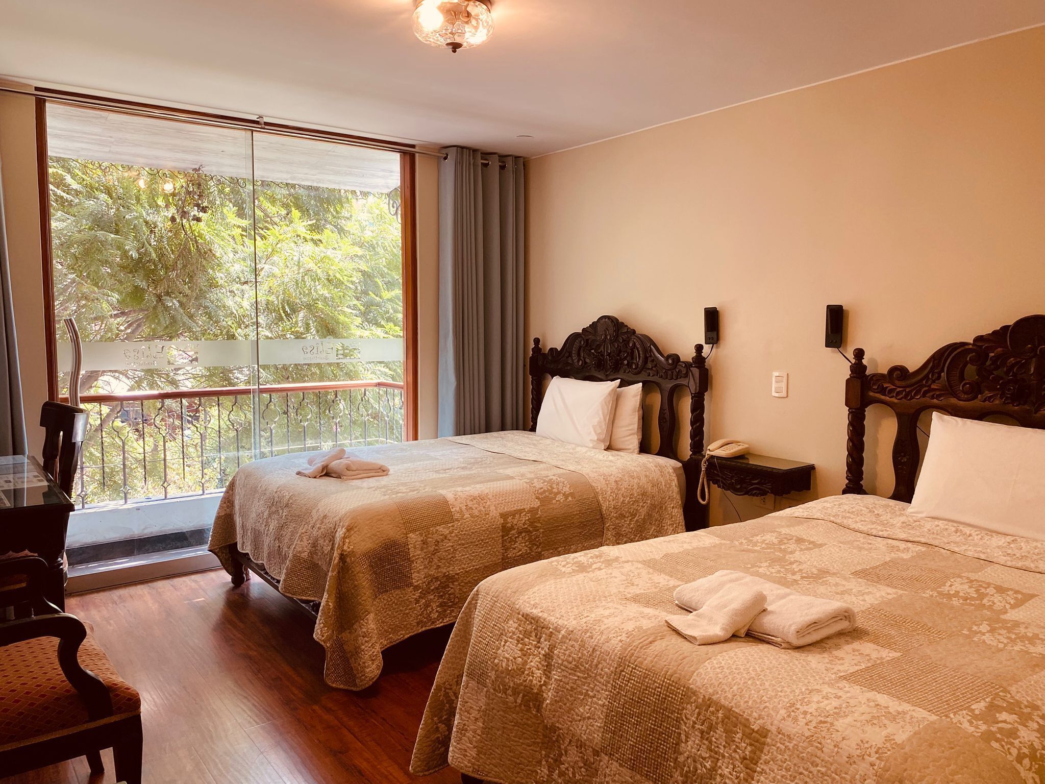 Habitación de hotel con dos camas, un balcón, un escritorio y una silla.