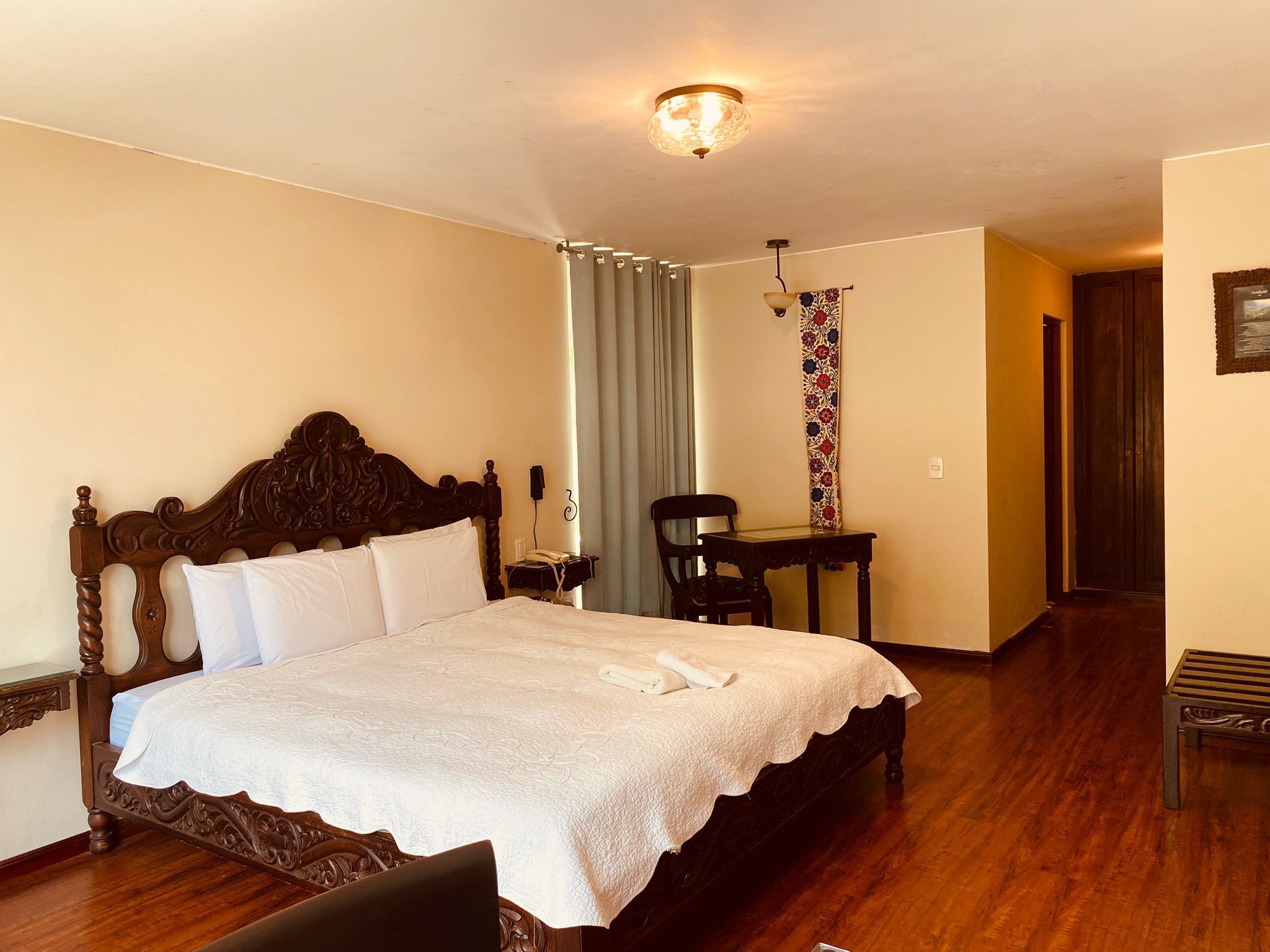 Habitación de hotel con una cama grande, un escritorio, una silla y una mesita.