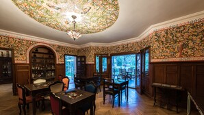 Un comedor con muebles de madera, una lámpara de araña y un techo estampado con motivos florales.