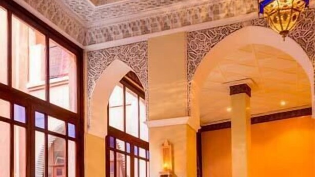 A hotel lobby with ornate arches, a central seating area with a round table, and a patterned floor. - Riad Marrakech House (Marrakech)