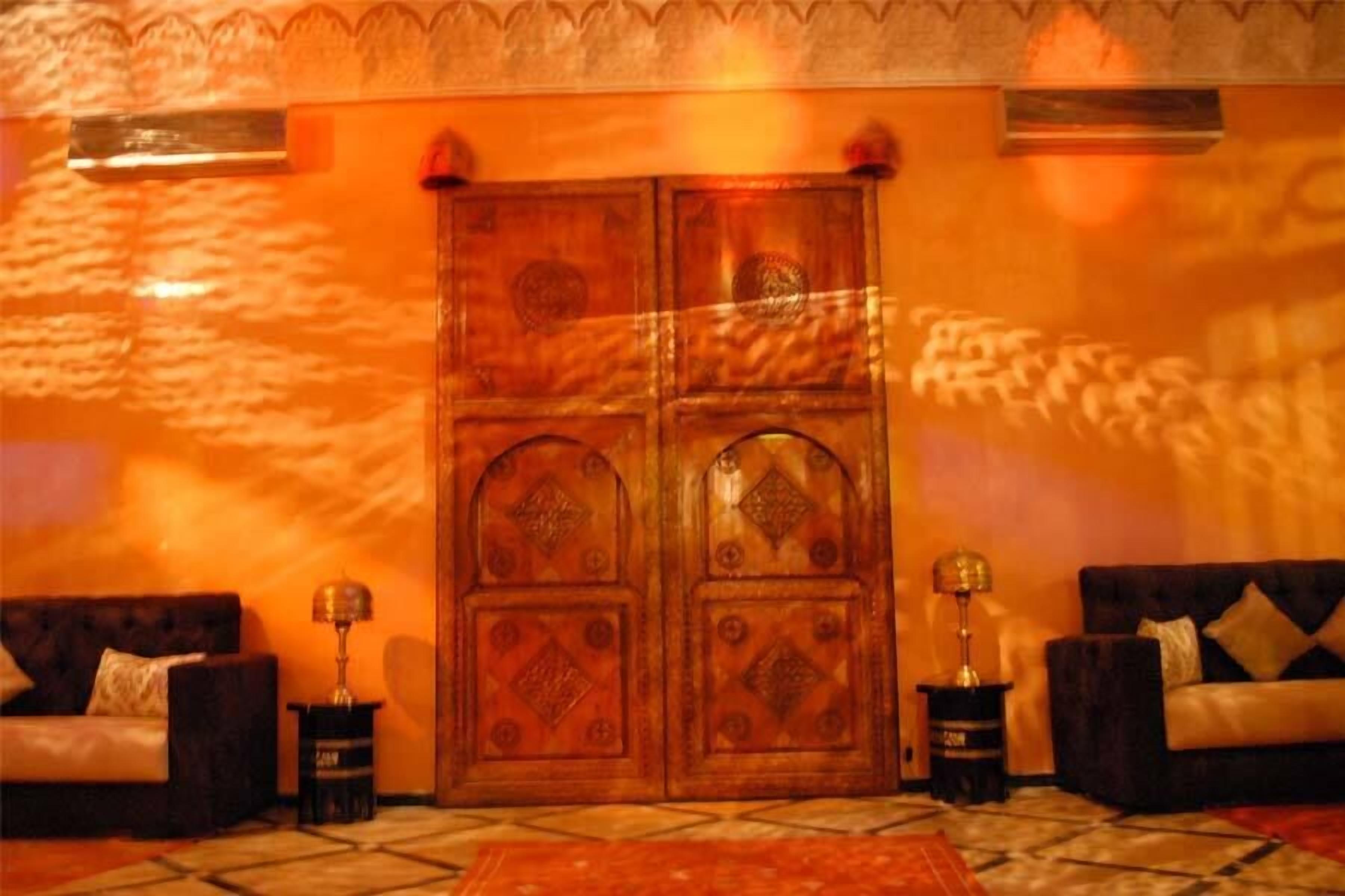 A room with a large wooden door, two sofas, and a patterned rug.