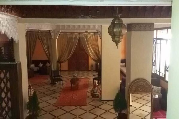 A traditional room with a tiled floor, a red carpet, a sofa, a coffee table, and a decorative lantern. - Riad Marrakech House (Marrakech)