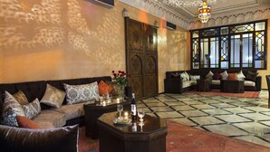 A spacious living area with a sofa, coffee table, and a decorative lamp. - Riad Marrakech House (Marrakech)