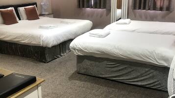 Una habitación de hotel con dos camas, una mesita y una silla.