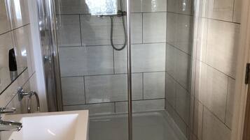Un baño moderno con ducha de vidrio, un lavamanos blanco y un tapete de toalla con la palabra 'Soda'.