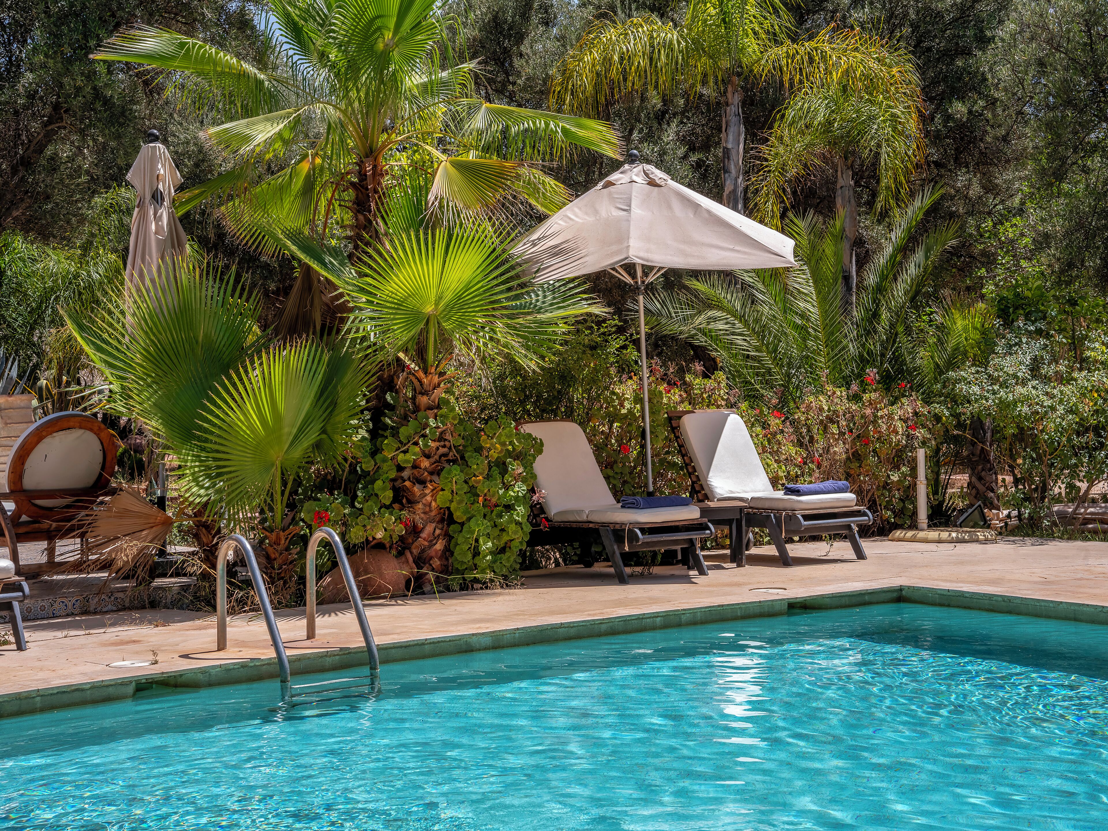 Een buitenzwembad, parasols bij het zwembad en ligstoelen