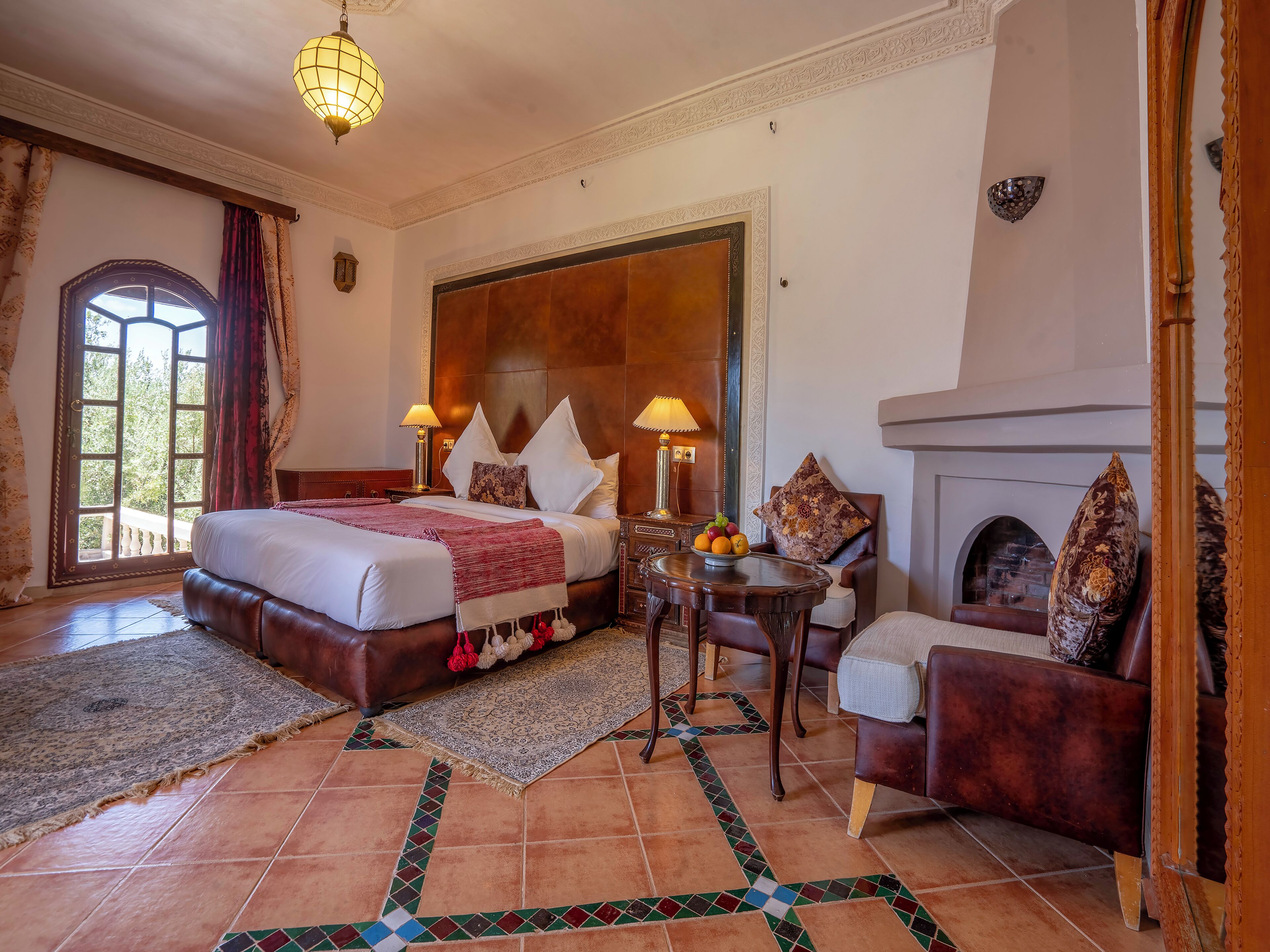Un dormitorio espacioso con una cama grande, una chimenea, una mesa de comedor y vistas al exterior por una ventana.