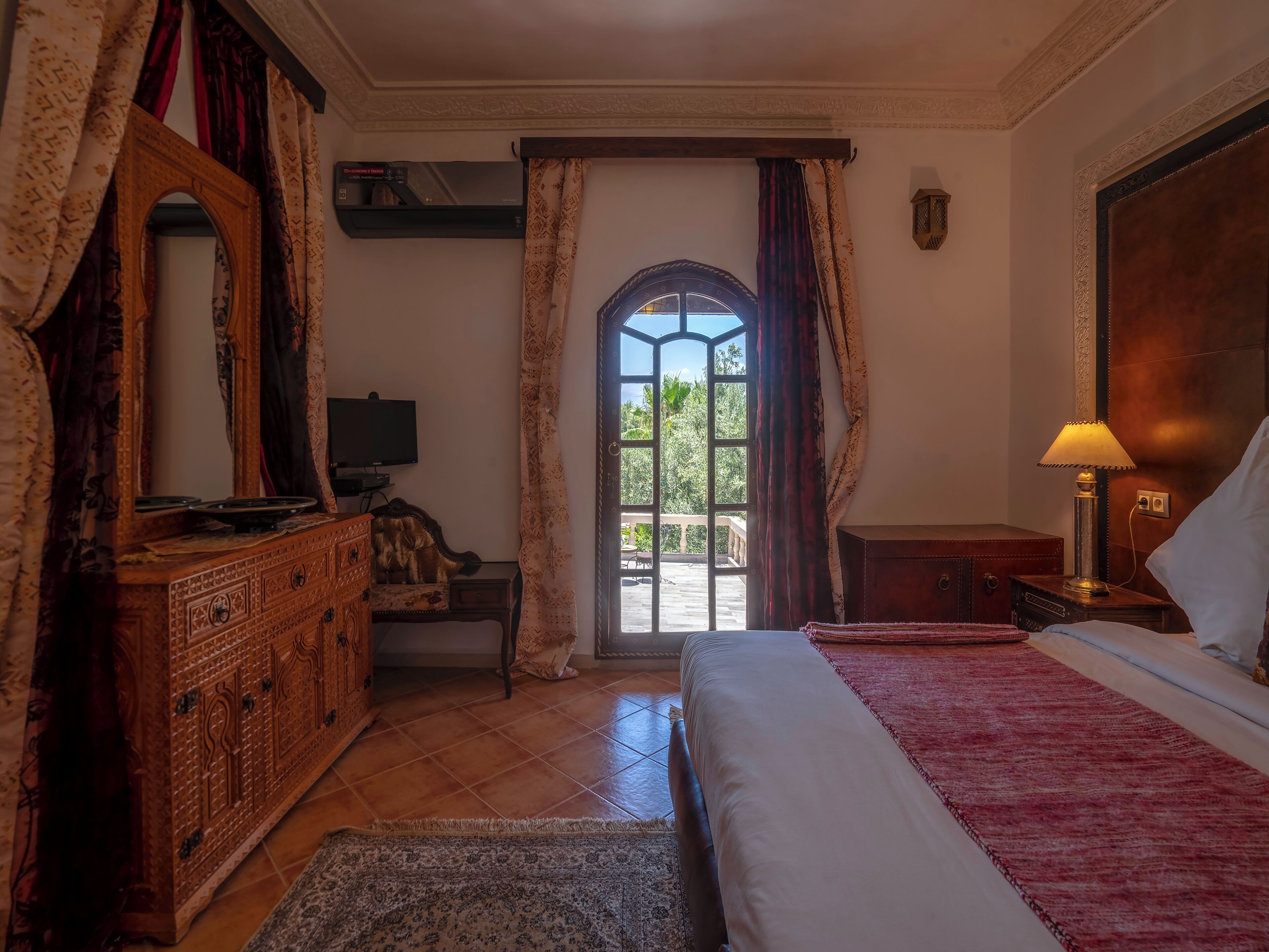 A bedroom with a bed, a dresser, a television, and a window with curtains.