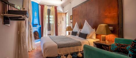 Un dormitorio amplio con una cama grande, un techo decorativo y vistas a un patio.