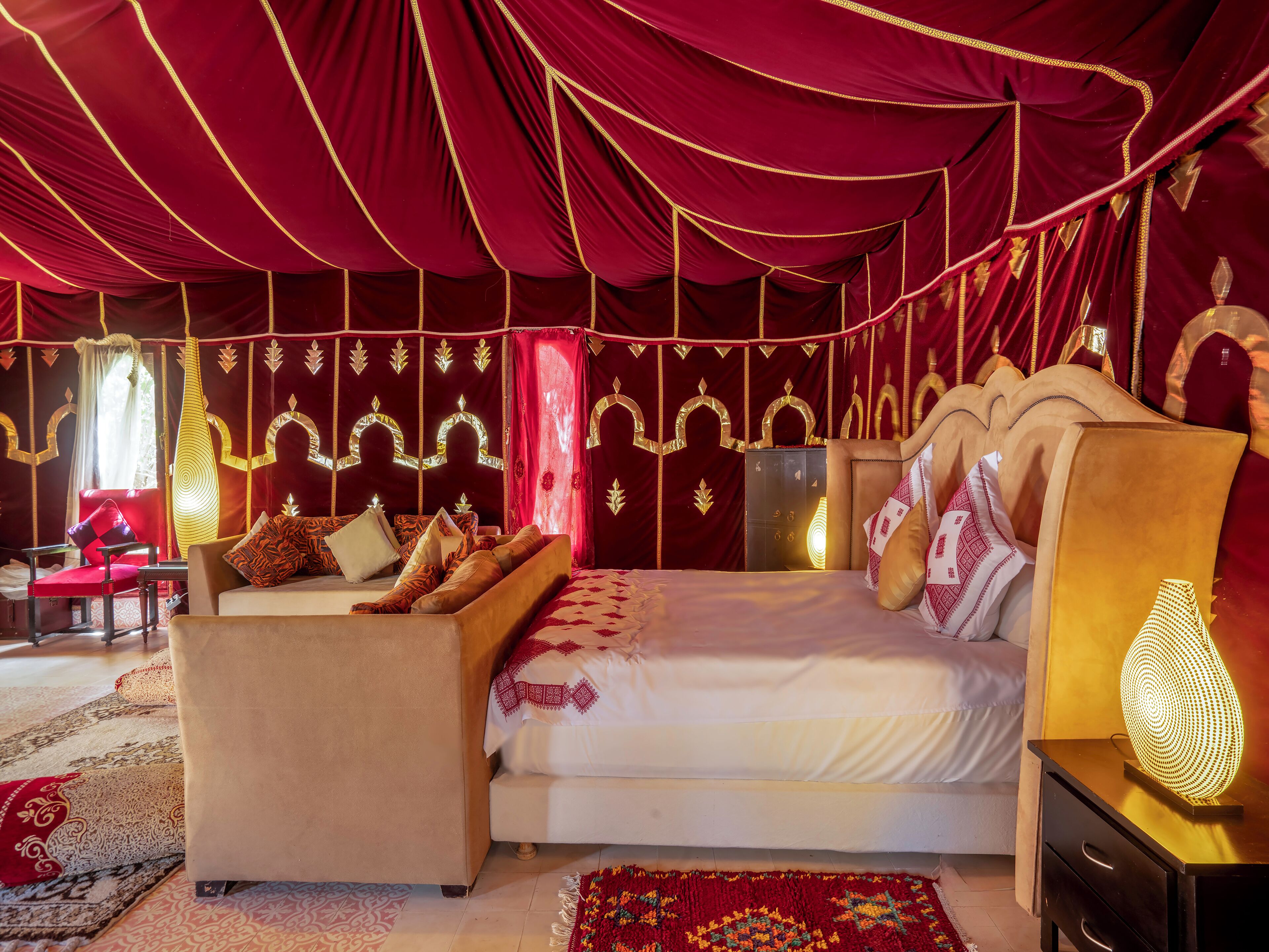 A luxurious room with a large bed, a sofa, and a nightstand.