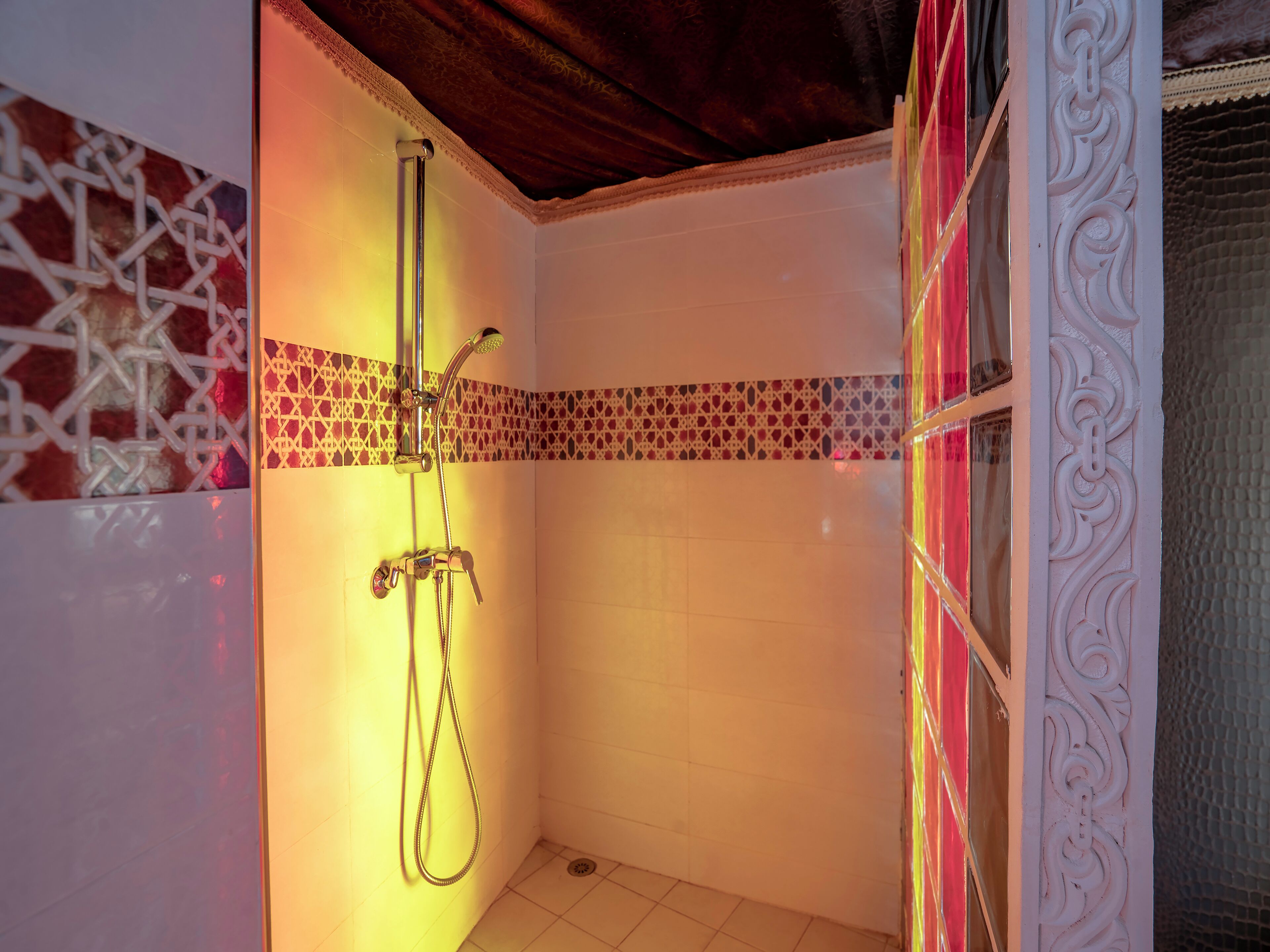 A small, tiled shower room with a showerhead and handheld shower attachment.