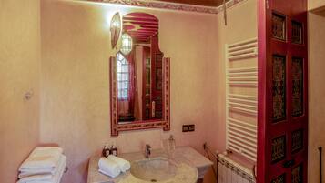A bathroom with a marble sink, a mirror, and a towel rack.