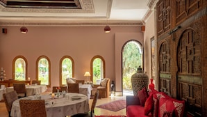 A dining area with tables set for four, a red sofa, and a large decorative vase.