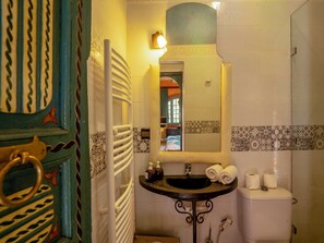 A bathroom with a white bathtub, a sink with two bottles of soap, and a toilet.