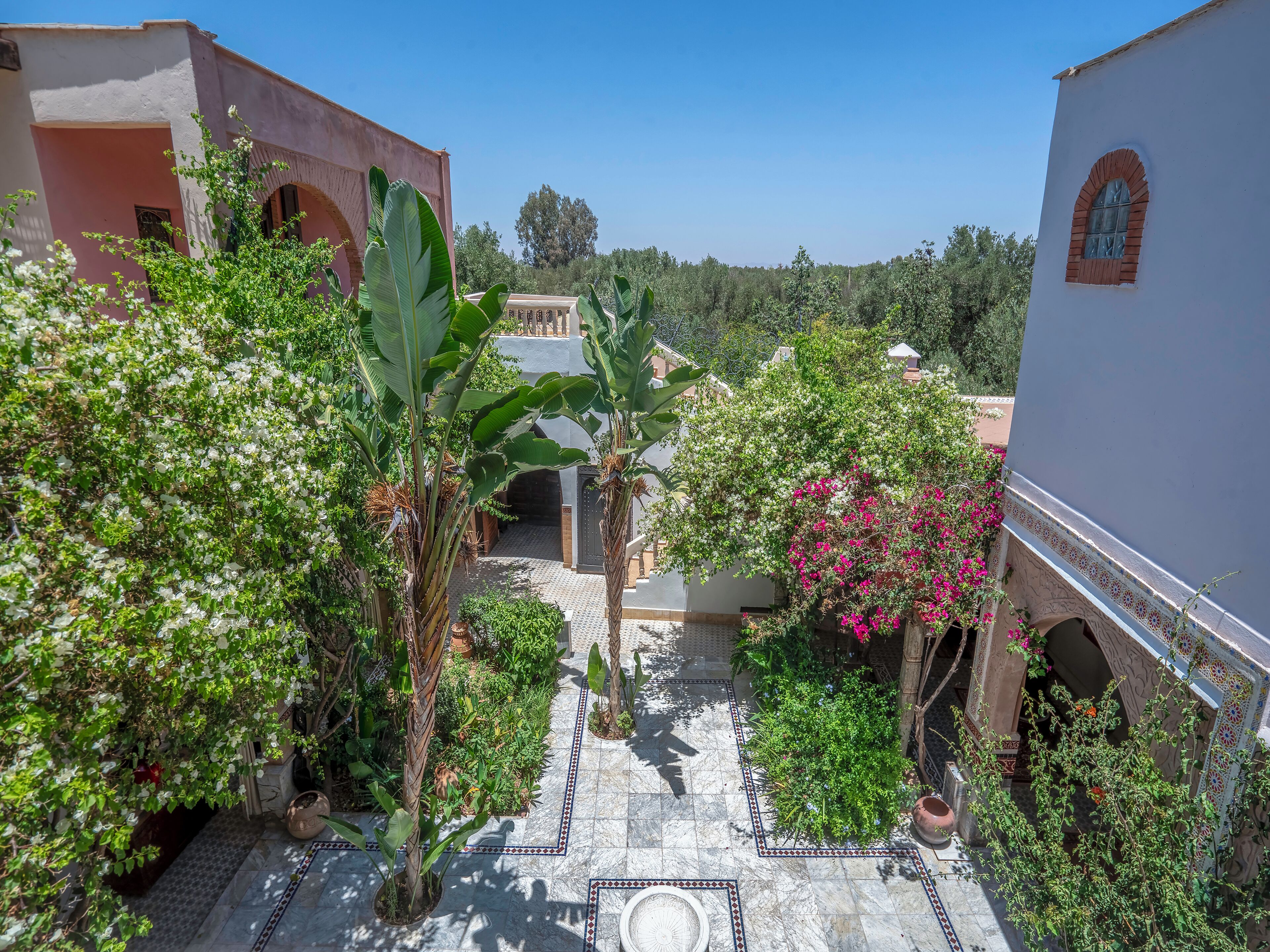 A courtyard with a tiled floor, surrounded by buildings with arches and a clear blue sky.