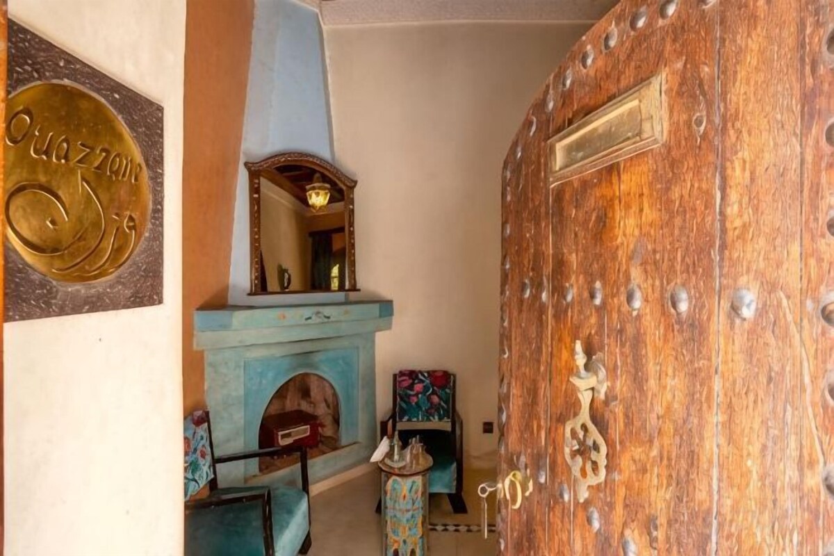 A room with a wooden door, a fireplace, and a blue sofa.