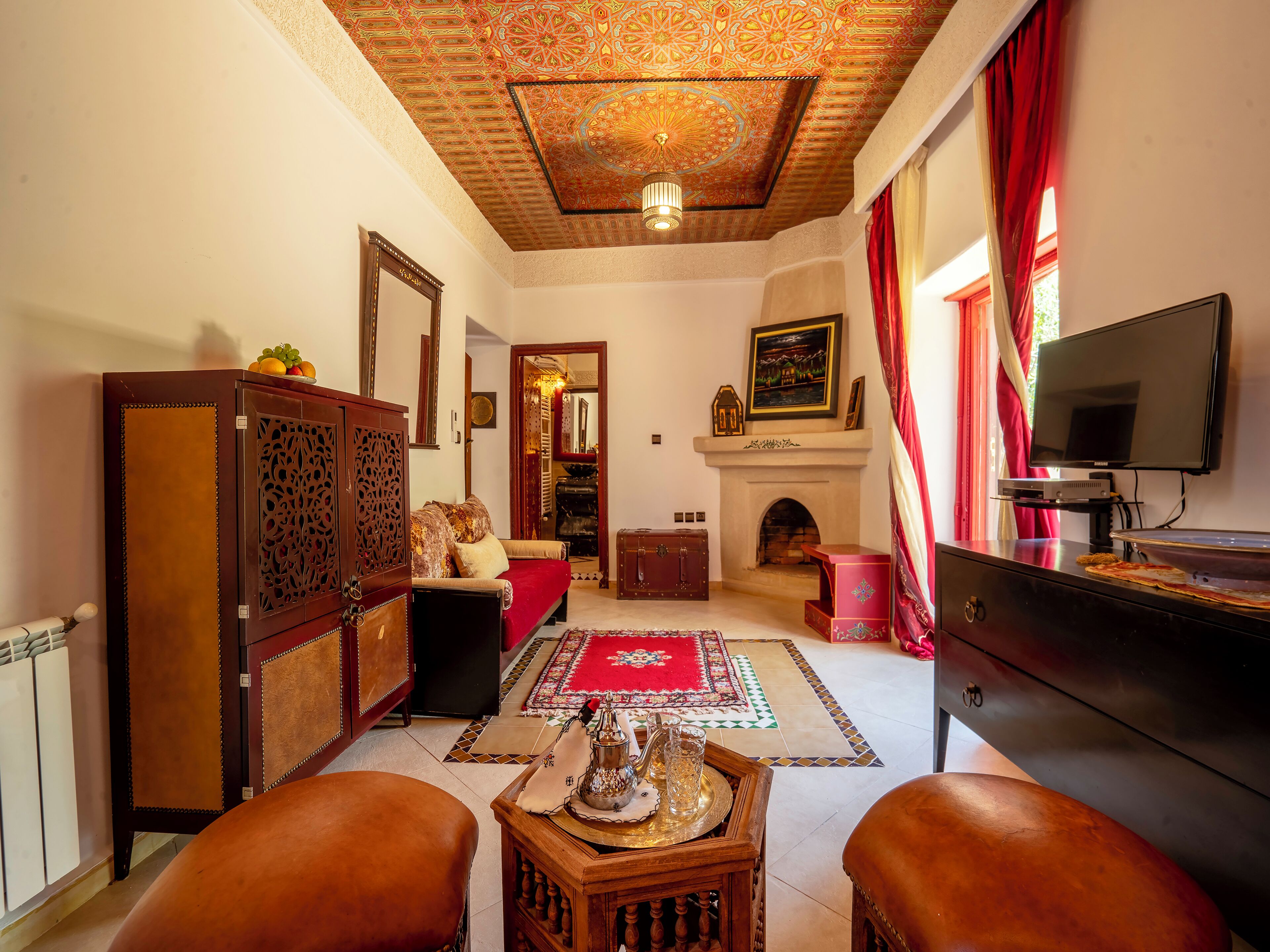 A traditional living room with a fireplace, a television, and a red carpet.
