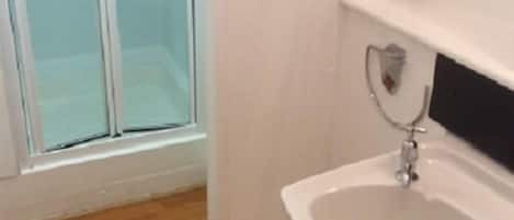 Un baño con lavamanos blanco, espejo y ducha.