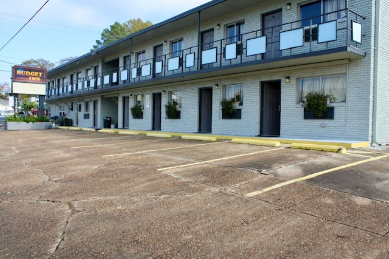 A motel with a row of rooms, a parking lot, and a sign for 'Budget Inn'.