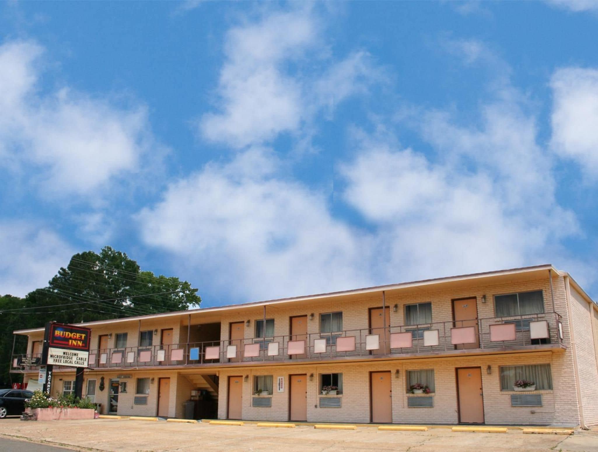 A two-story motel with a signboard advertising free local calls and a welcome message.