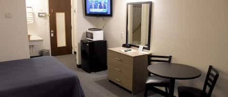 Ein Hotelzimmer mit zwei Betten, einem Schreibtisch mit Stuhl, einem Fernseher, einer Mikrowelle und einem Spiegel.