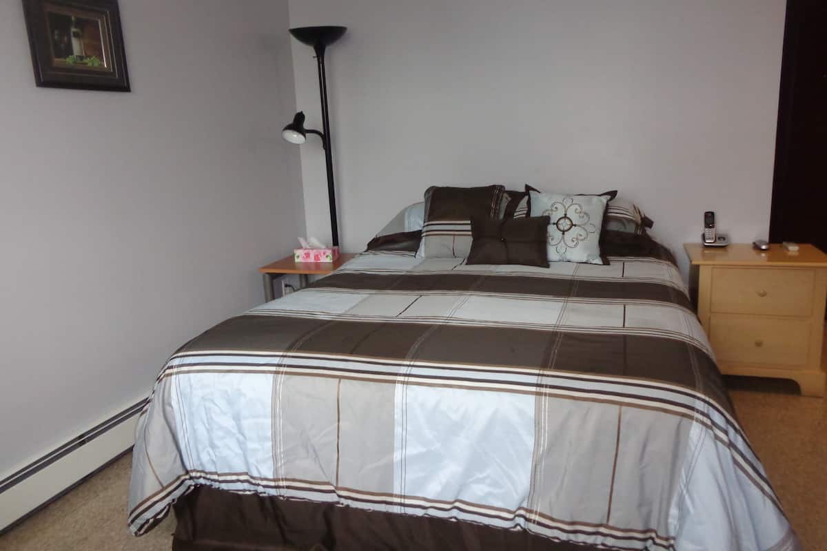 A bedroom with a bed, bedside tables, a lamp, and a framed picture on the wall.