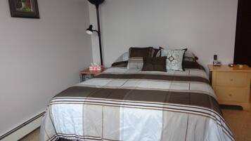Une chambre à coucher avec un lit, des tables de chevet, une lampe et un tableau encadré au mur.