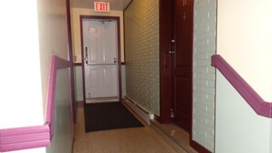 A hallway with an exit sign, a double door, and a brick wall. - Happy Motel (Edmundston)