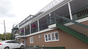 A two-story building with a balcony and a staircase. - Happy Motel (Edmundston)