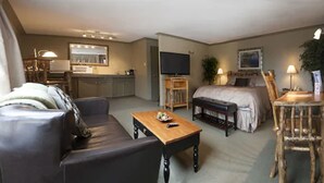 Una sala de estar moderna con sofá, mesa de centro y televisor. Hay un comedor con mesa y sillas, y un dormitorio con cama y mesita de noche.