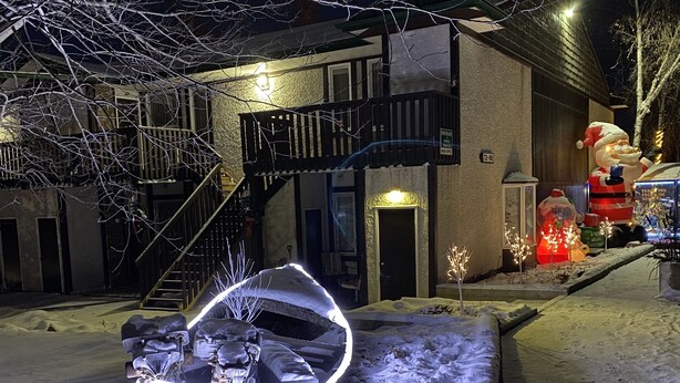 Una calle cubierta de nieve con un edificio que tiene una escalera de emergencia y una gran escultura iluminada.
