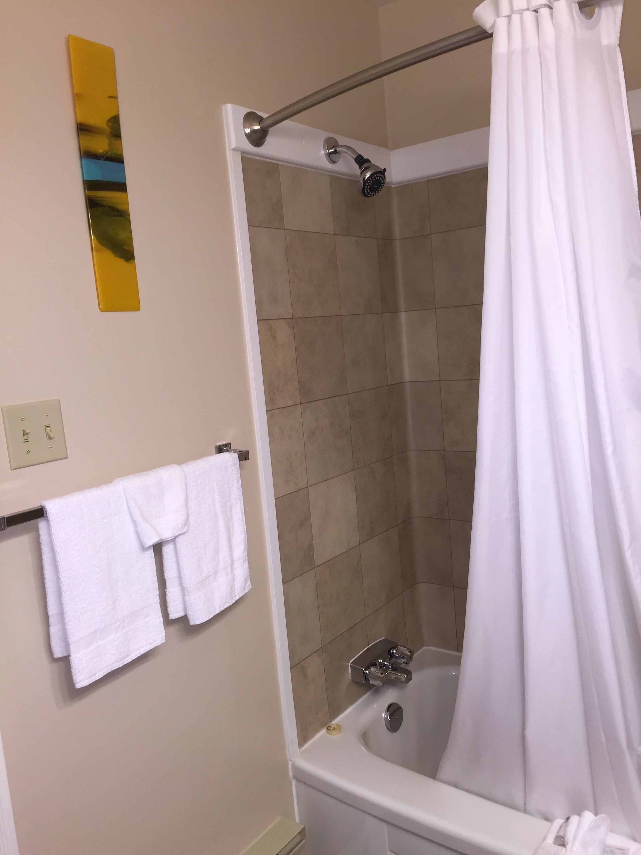 A bathroom with a bathtub, a shower curtain, and a towel rack with two towels.