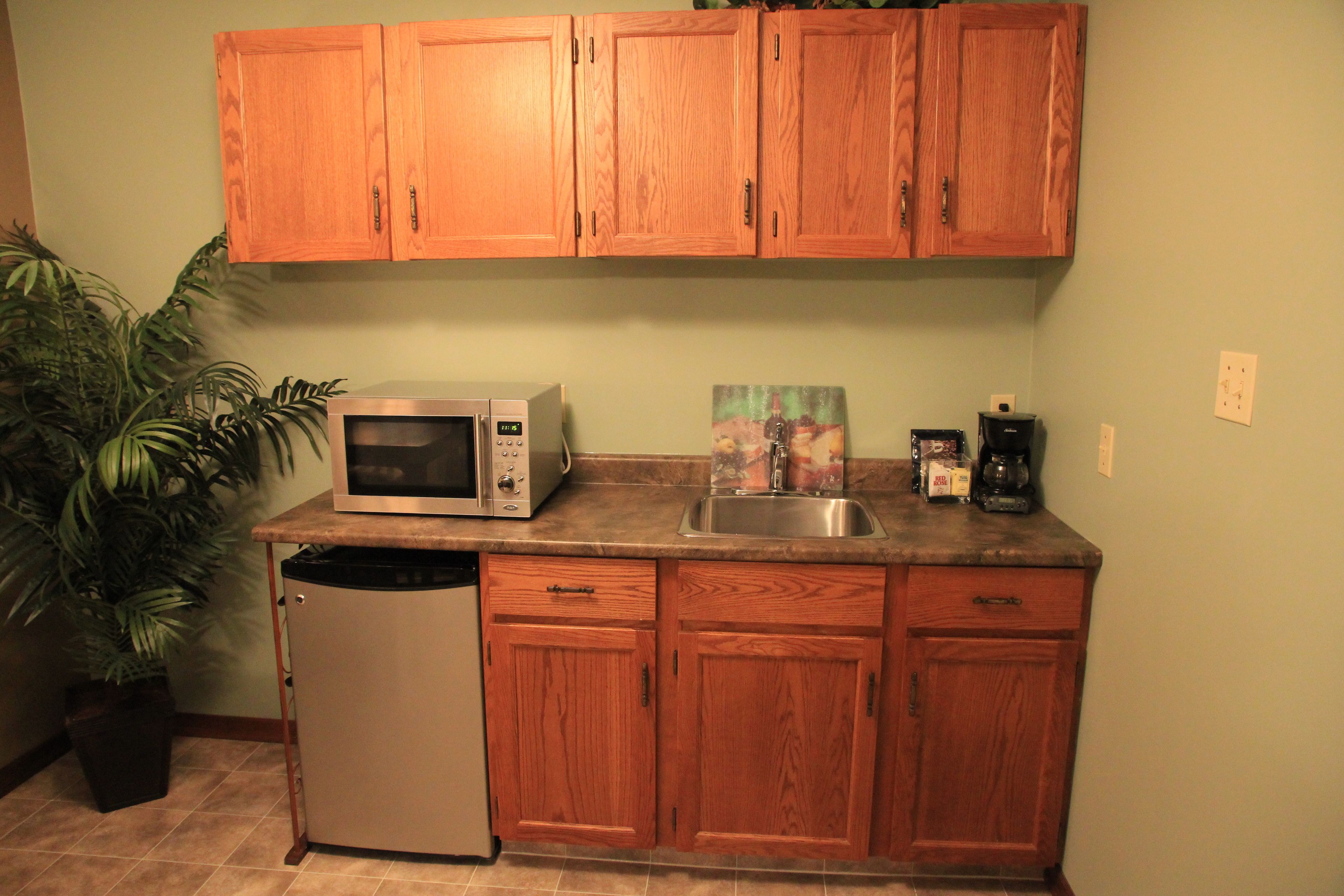 A kitchen with wooden cabinets, a microwave, a sink, and a dishwasher.
