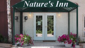 Posada Nature's Inn con un toldo verde, puertas dobles y plantas en macetas.