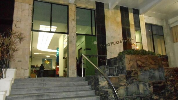 A hotel entrance with a staircase leading up to the lobby, featuring a reception desk and a large window. - Titao Plaza Hotel (Campina Grande)