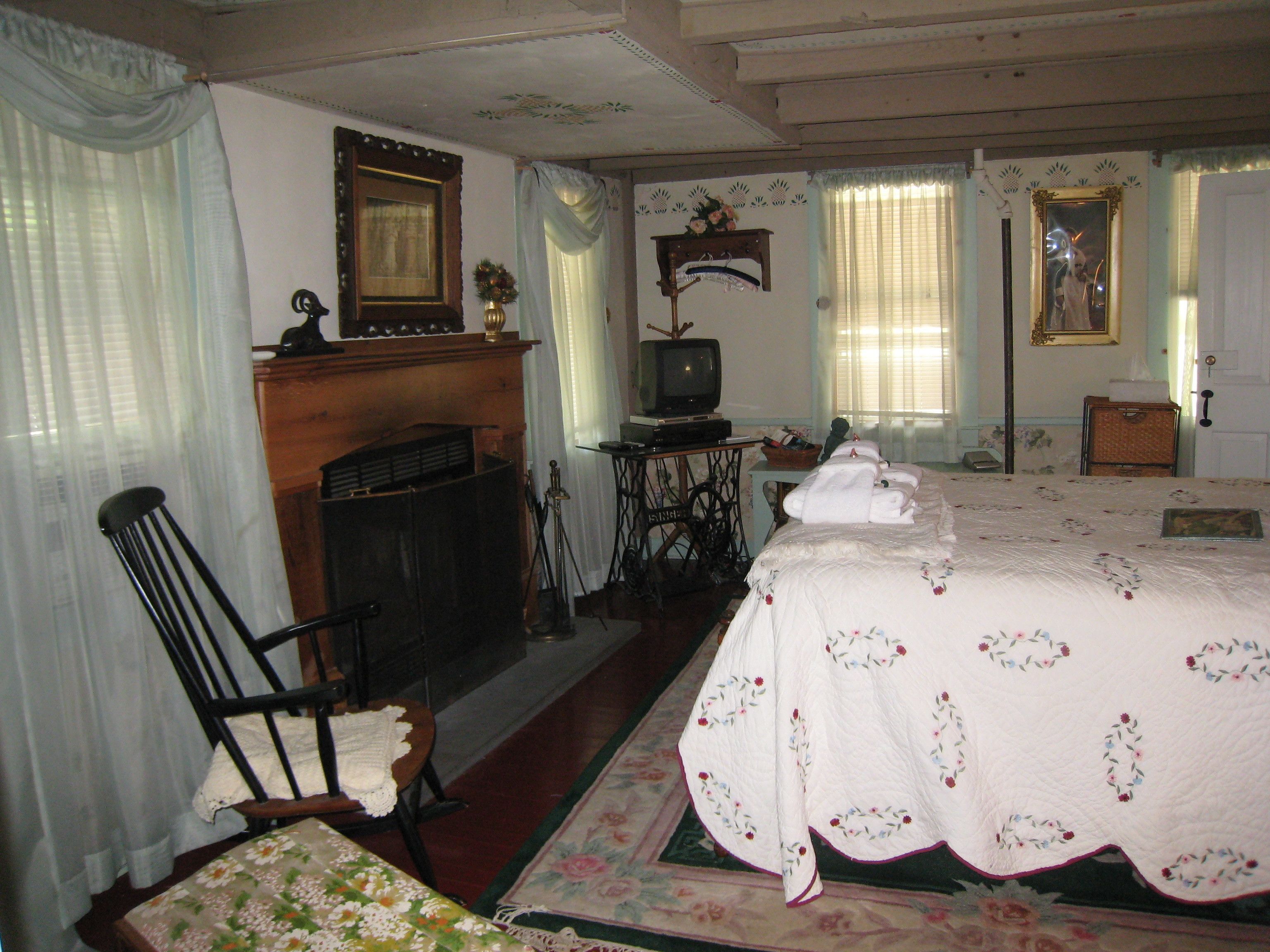 Una habitación tradicional con chimenea, una cama con ropa de cama estampada, una silla y un televisor.