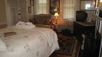 Un dormitorio con una cama grande, un aparador, un televisor y una lámpara.