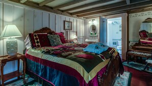 A bedroom with a large bed, a bedside table with a lamp, a dresser, and a mirror. - Captain Grant's 1754 (Preston)