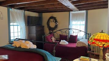 Una habitación con dos camas, techo de madera, televisor y una lámpara decorativa.
