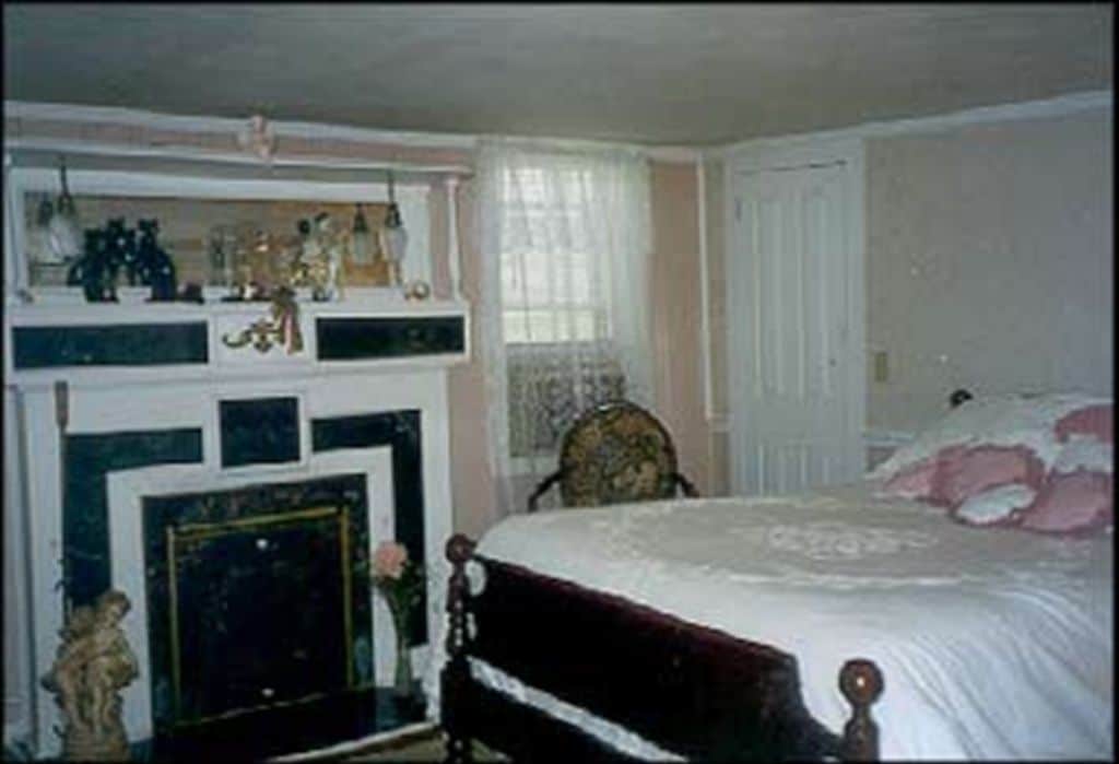 Un dormitorio con cama, cómoda, espejo y chimenea.