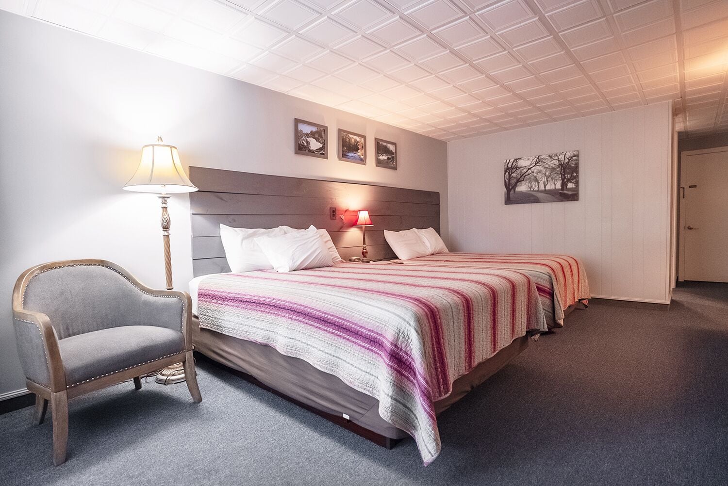 A hotel room with a large bed, two bedside tables, a chair, and a lamp.