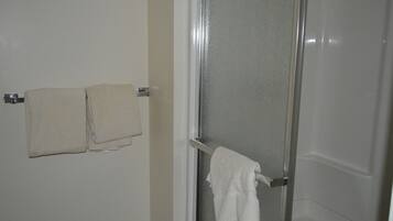 Un baño con mampara de vidrio, un perchero con dos toallas y una pared lisa.