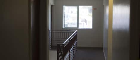 Un pasillo con una señal de salida, una ventana y una escalera.